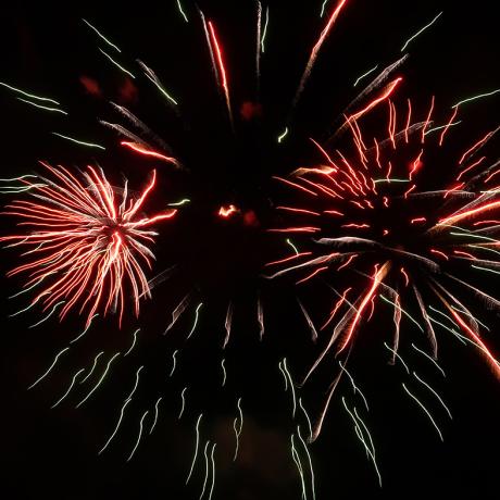 Plusieurs fleurs d'artifice rouge et blanche avec leurs trainées