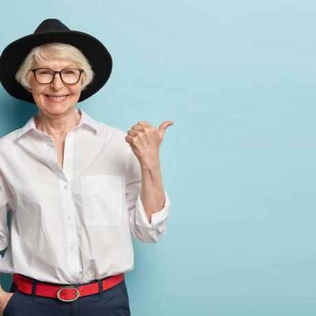 Une dame avec cheveu blanc et chapeau fait du stop sur fond bleu